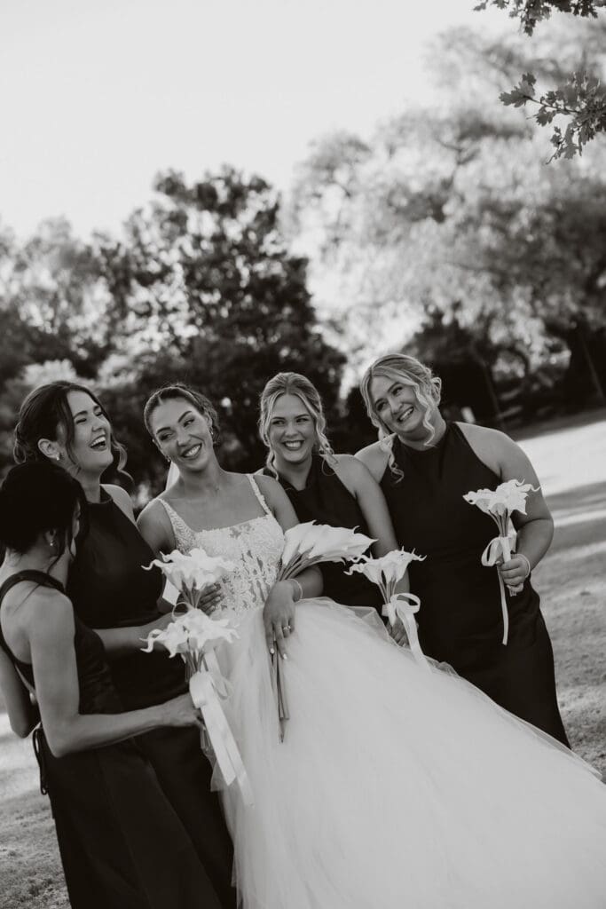 Bride laughing with her bridesmaids, each holding calla lily bouquets styled by Bless Events