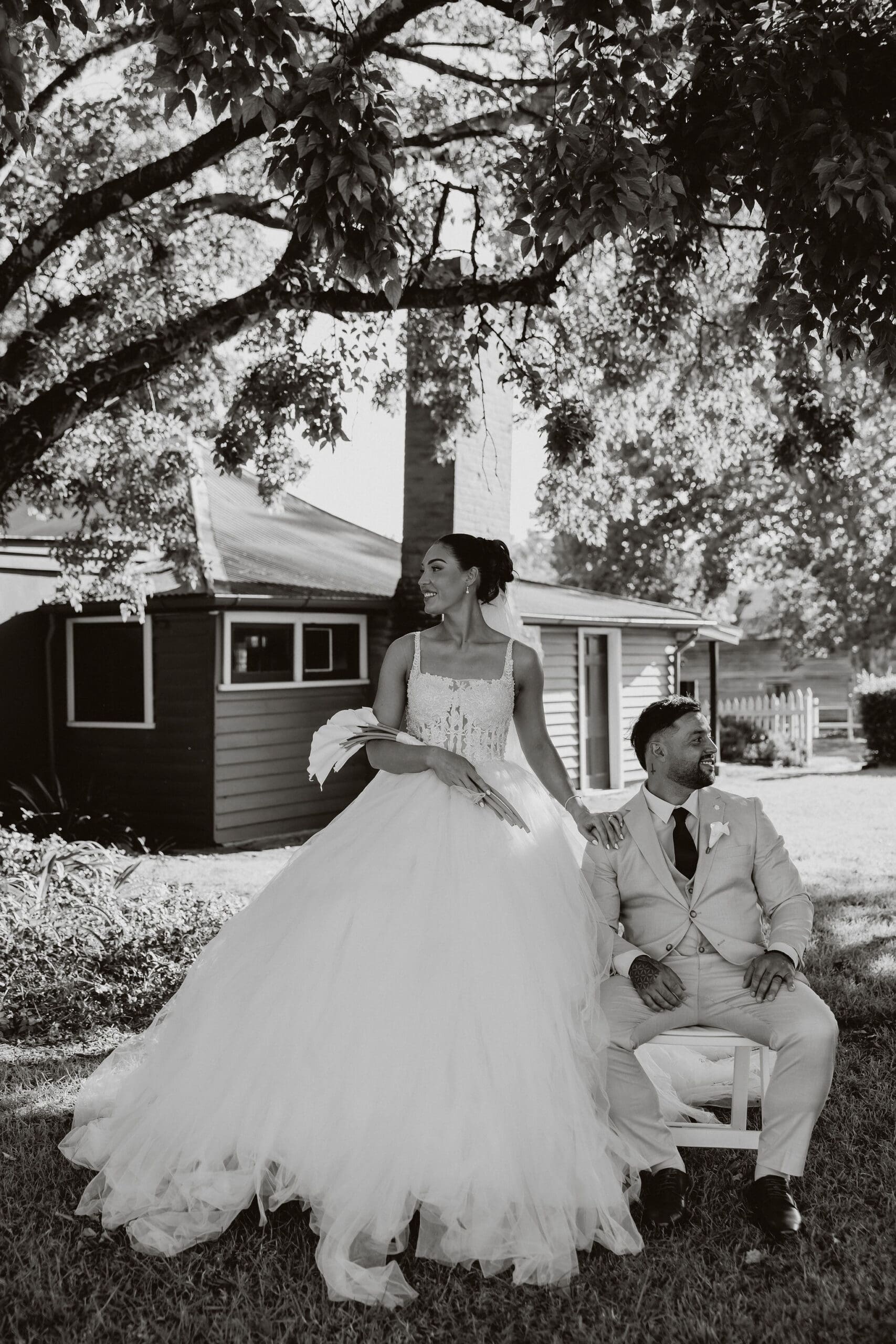 Bride and groom laughing together under a tree at their rustic farm wedding