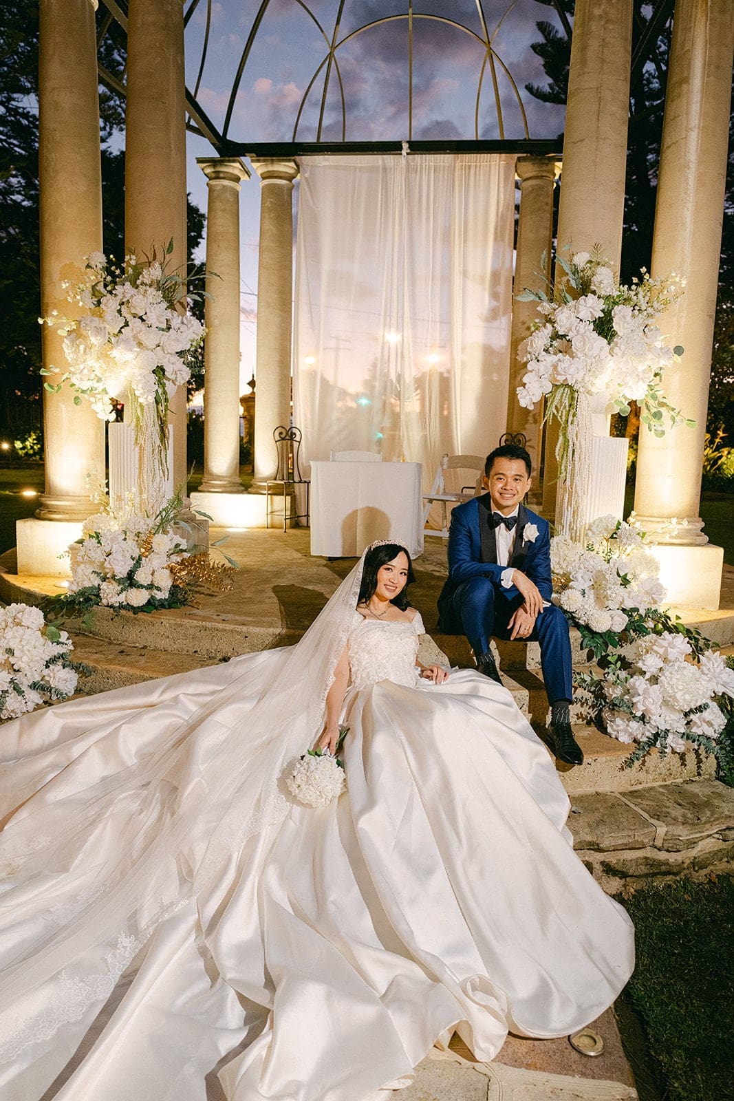 Outdoor ceremony setup by Bless Events, featuring bride and groom sitting on sandstone staircase at Curzon Hall, Marsfield