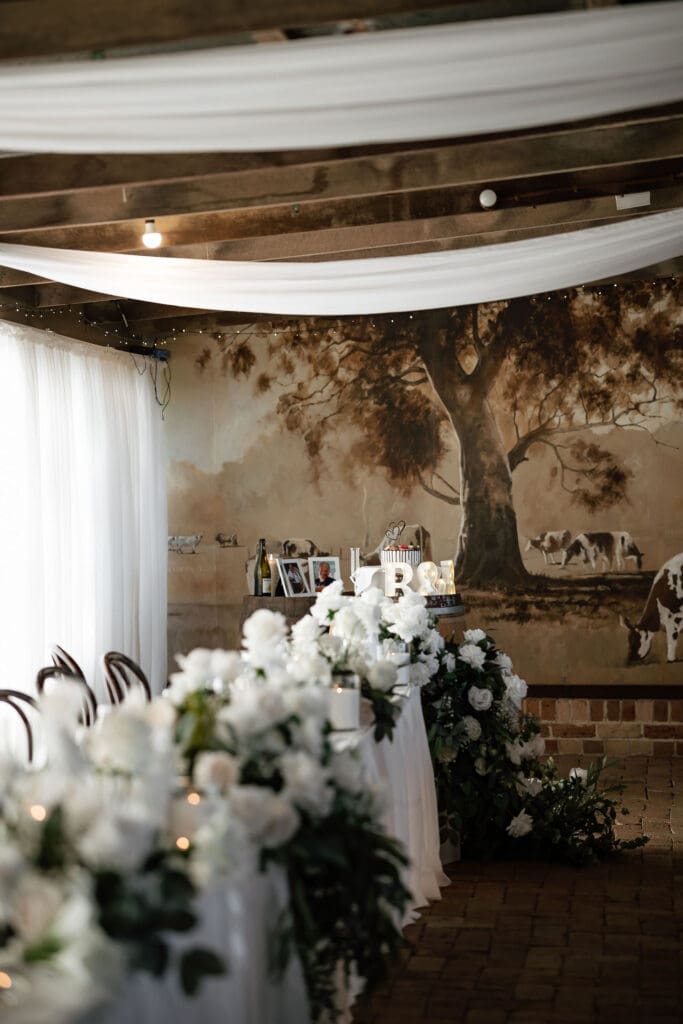 Faux rose and greenery garland along a Sydney wedding reception table with draped linen and candlelight