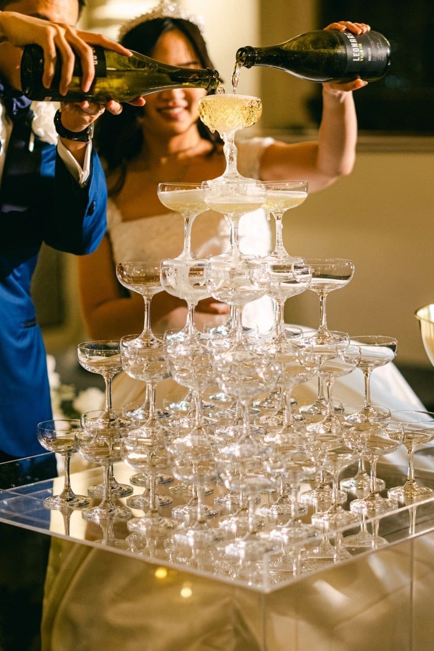 Bride and groom pouring champagne on champagne tower set up by Bless Events
