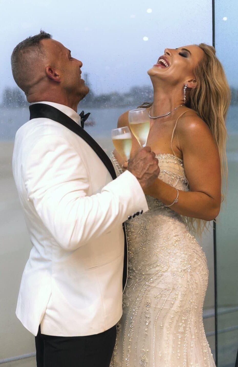 Bride and groom laughing together while toasting champagne at their Sydney wedding reception