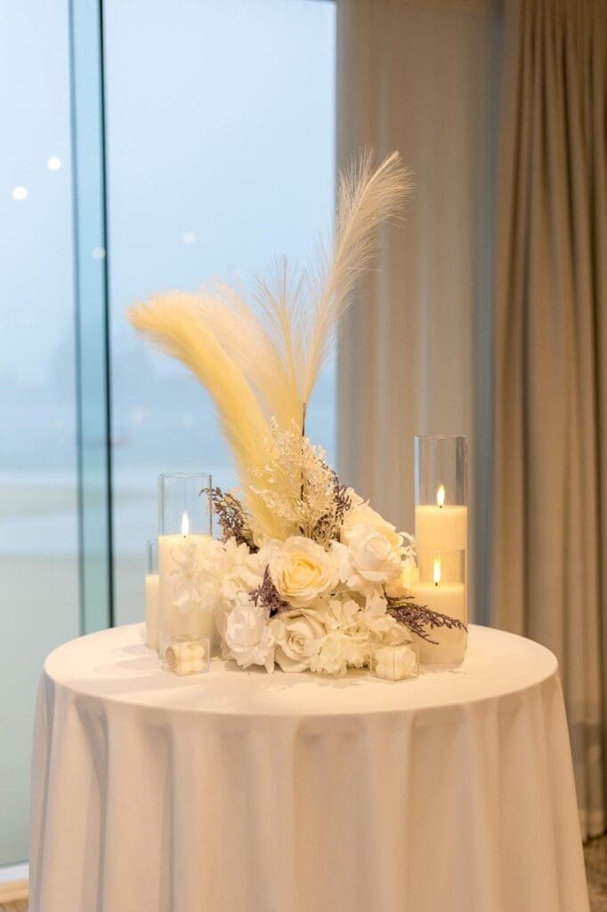 Cocktail table styled with pampas grass, white roses and pillar candles as a standalone feature setup