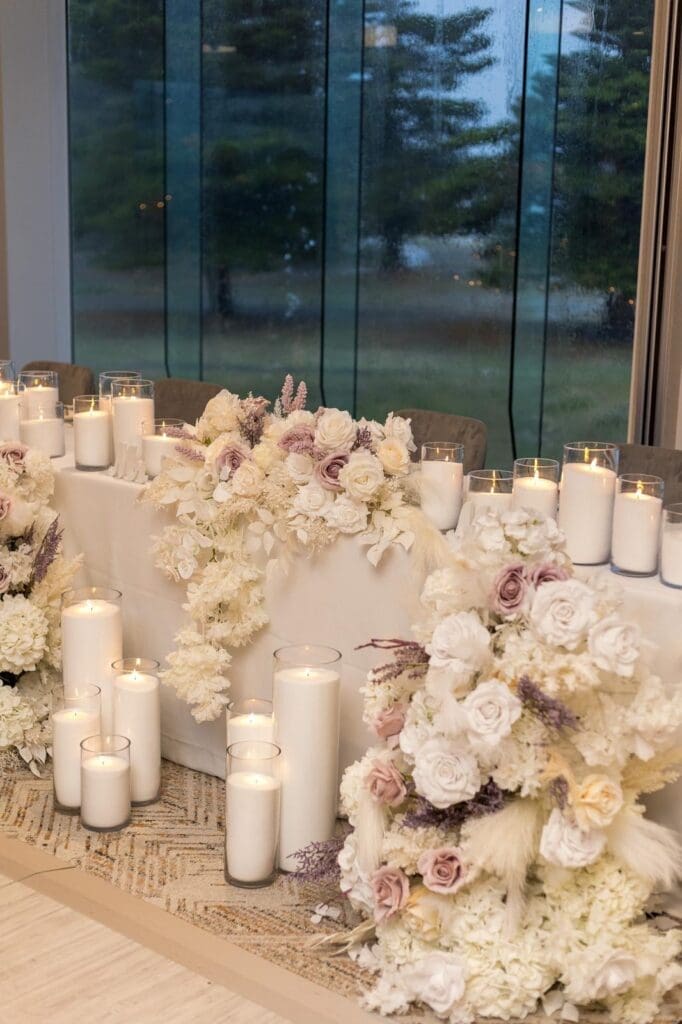Close-up of a faux floral and candle table runner in white, blush and mauve tones